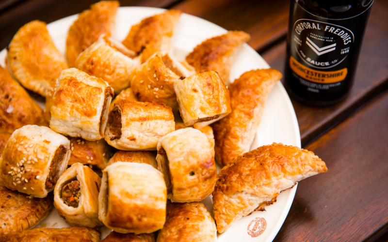 Sausage Rolls on a plate with Corporal Freddies Worcestershire sauce bottle in the background