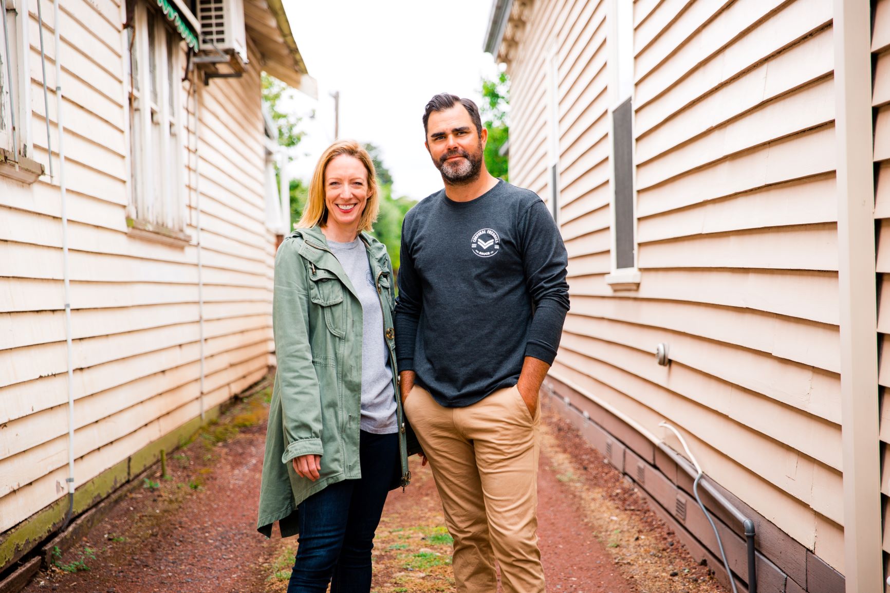 Keri & Mike, founders of Corporal Freddies standing outside a weatherboard home and smiling