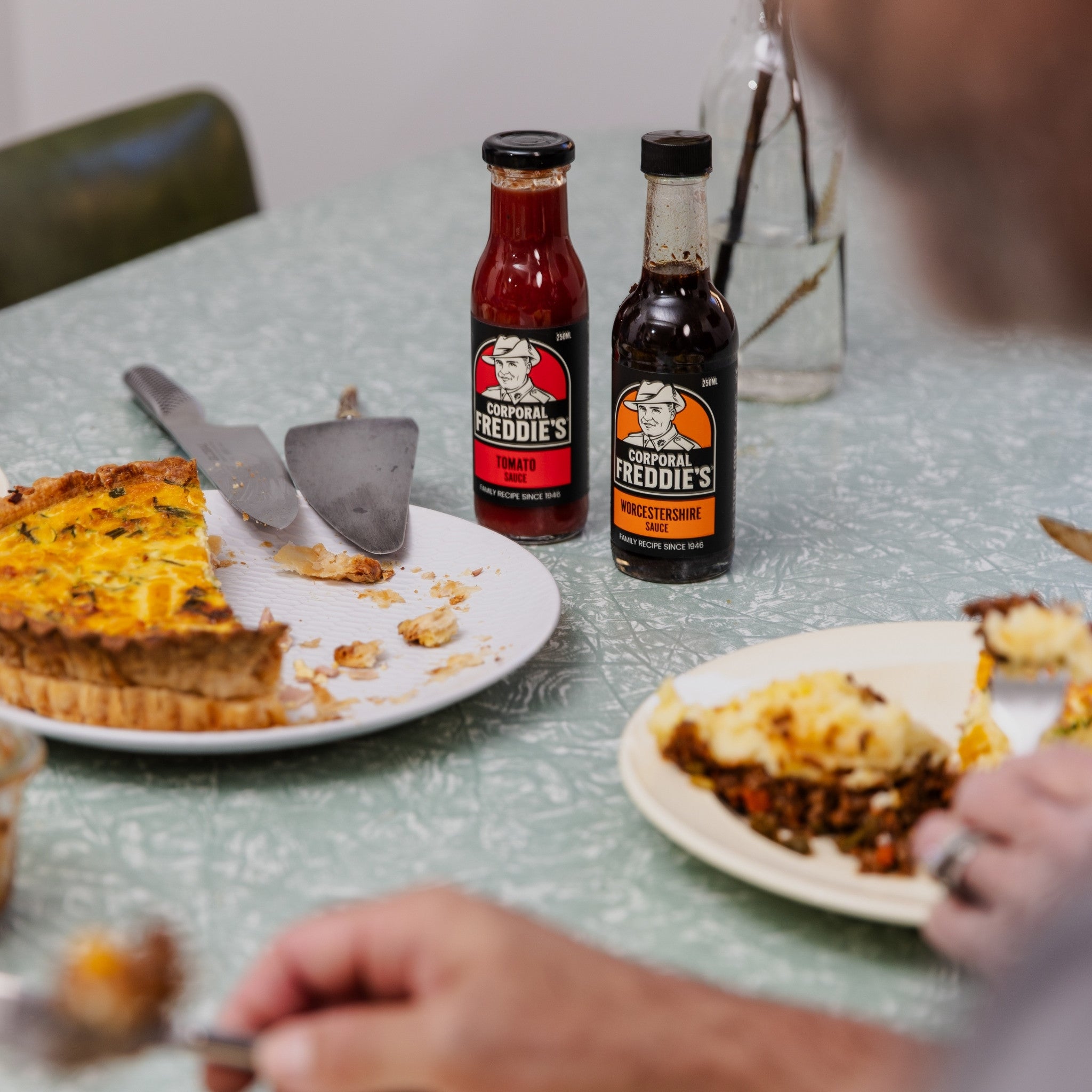 Bottles of Tomato and Worcestershire Sauces on table with plates of food