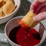 Person dipping a sausage roll into a bowl of tomato sauce