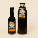 Two bottles of Corporal Freddie's Worcestershire sauce on a beige background