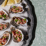 Oysters kilpatrick on a bed of salt with garnishes on a textured surface