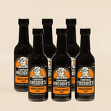 Six bottles of Corporal Freddie's Worcestershire sauce on a beige background